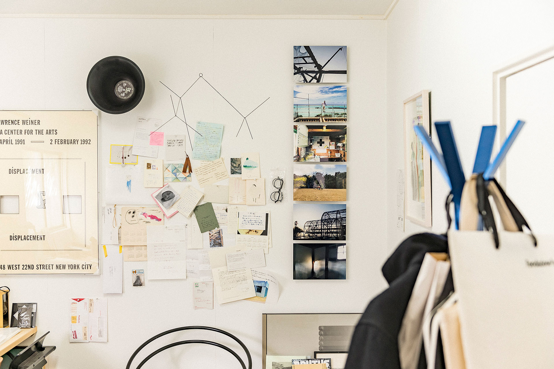 白い壁に縦一列に並ぶWALL DECOR ミュージアムと、その周囲にポスターやメモ、スケッチがコラージュのように飾られたクリエイティブなアトリエの壁面。