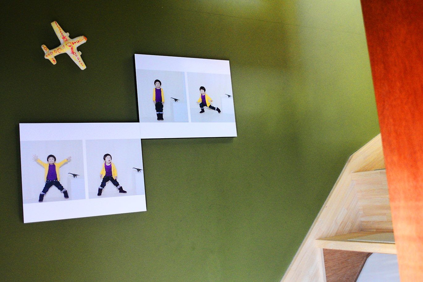 緑の壁に飾られたWALL DECORにプリントされた子供の写真