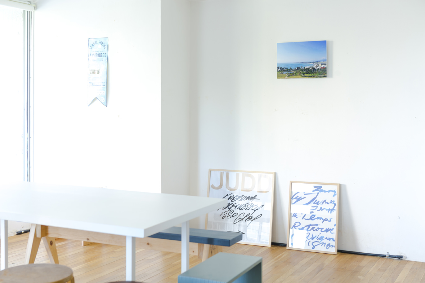 壁にWALL DECORが飾られている白い部屋。手前に白いテーブルと椅子がある