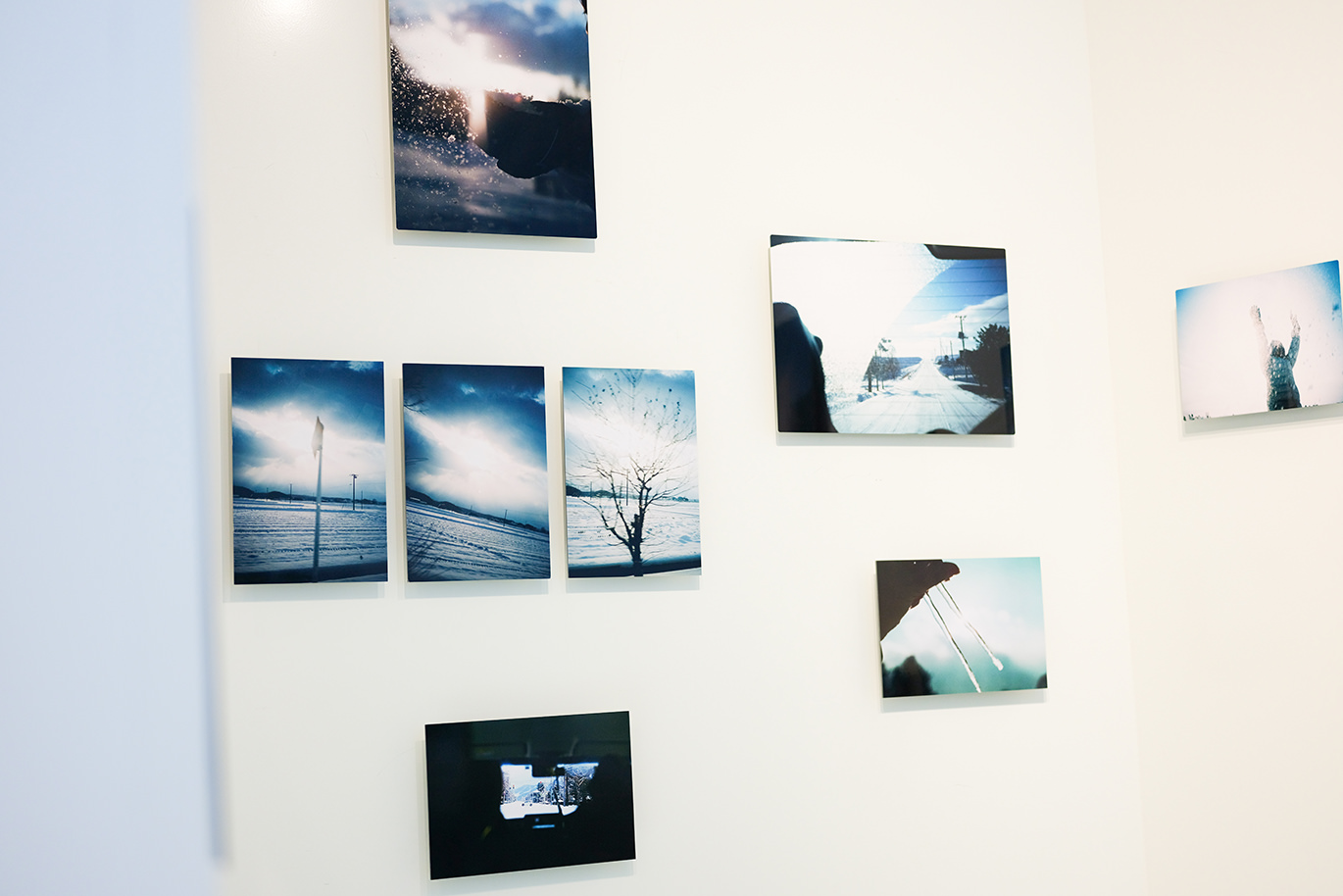 白い壁にランダムに配置して飾られた、雪景色や光の風景写真のWALL DECOR