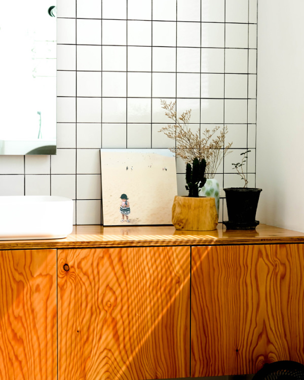 白いタイルの壁と木の洗面台に、砂浜に立つ子供の写真のWALL DECORと植物