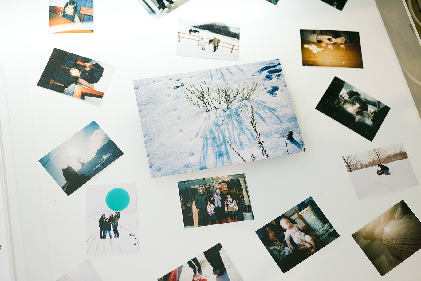 テーブルの上に並べられた雪景色の写真のWALL DECORと、家族や風景など様々なスマホ・デジカメプリント