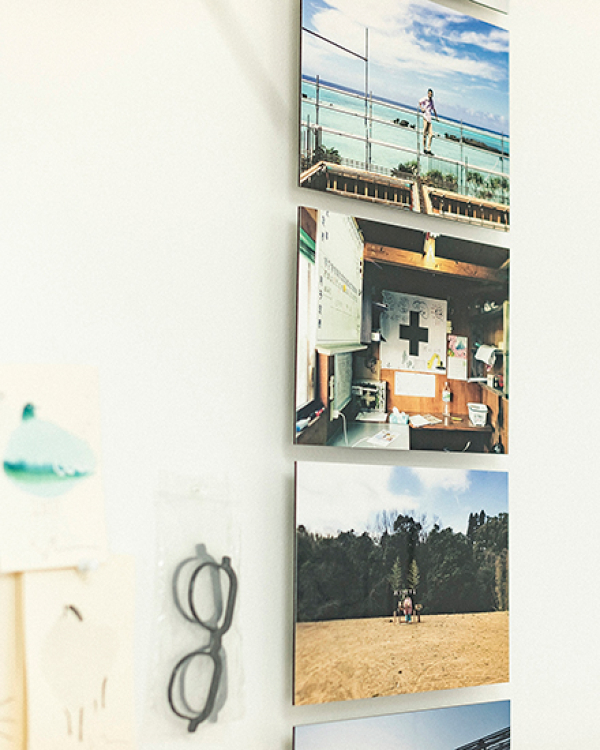 白い壁に縦に並べて飾られた、海や森などの風景や人物の写真のWALL DECOR。