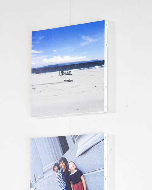 白い壁に縦に並べて飾られた、砂浜の風景と笑顔の子供たちの写真のWALL DECOR。