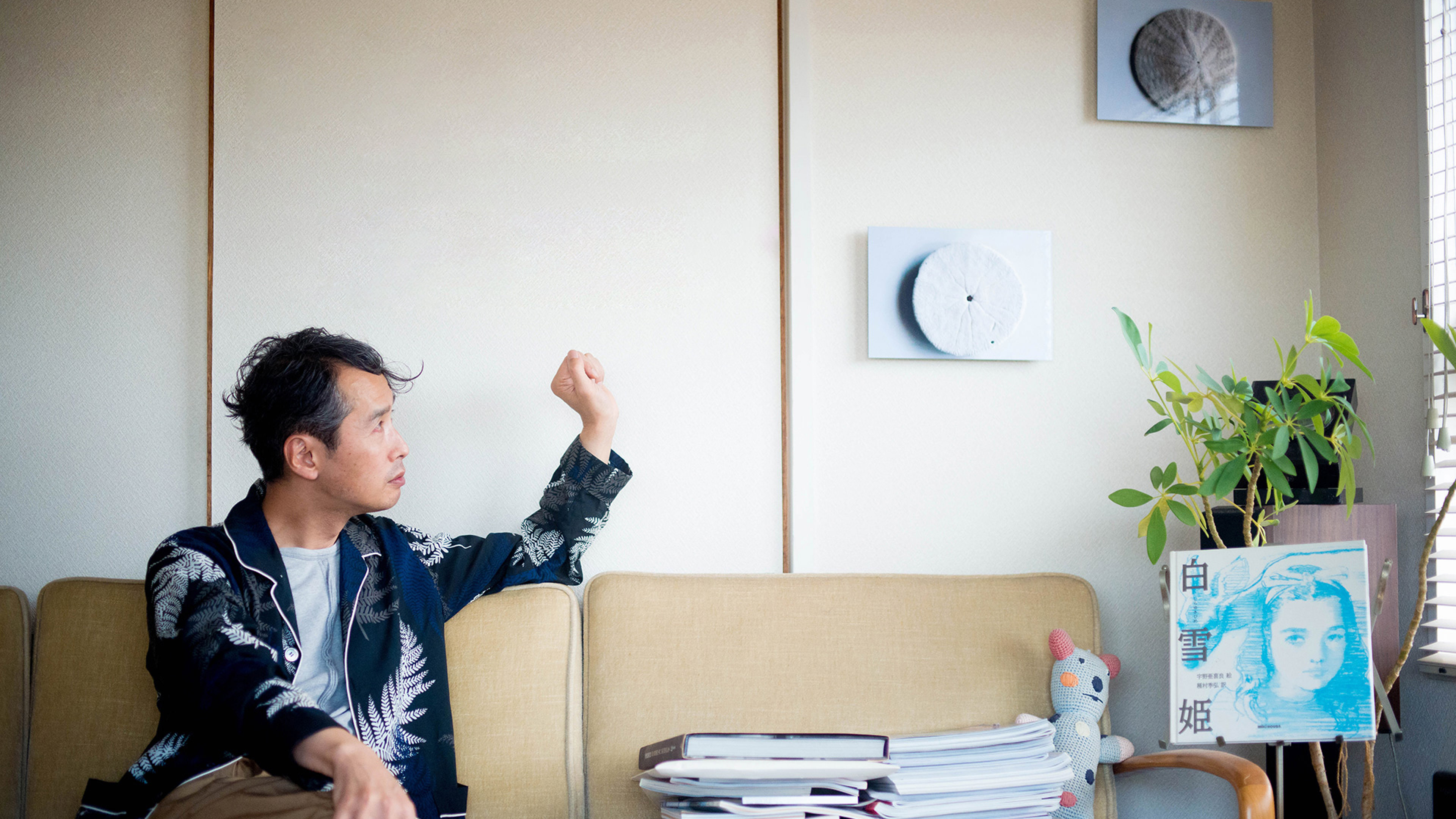 壁に飾られた、円形のアート作品のWALL DECOR ミュージアム。ソファに座る男性や観葉植物がある落ち着いた室内にディスプレイされている。