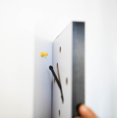 壁に刺した画鋲にWALL DECOR カジュアルを掛けて取り付ける様子