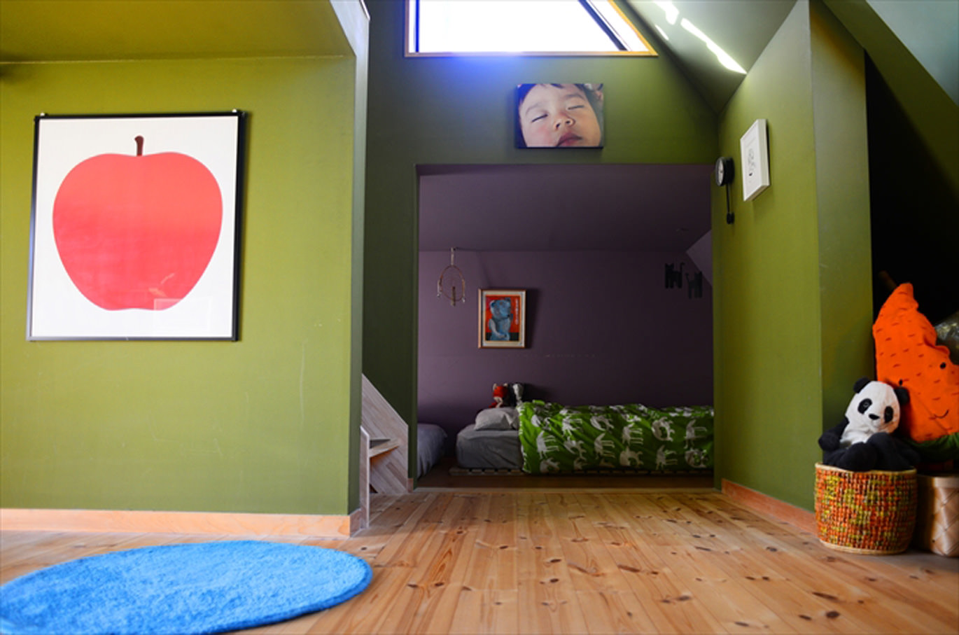 緑の壁とアートが飾られた子供部屋の風景