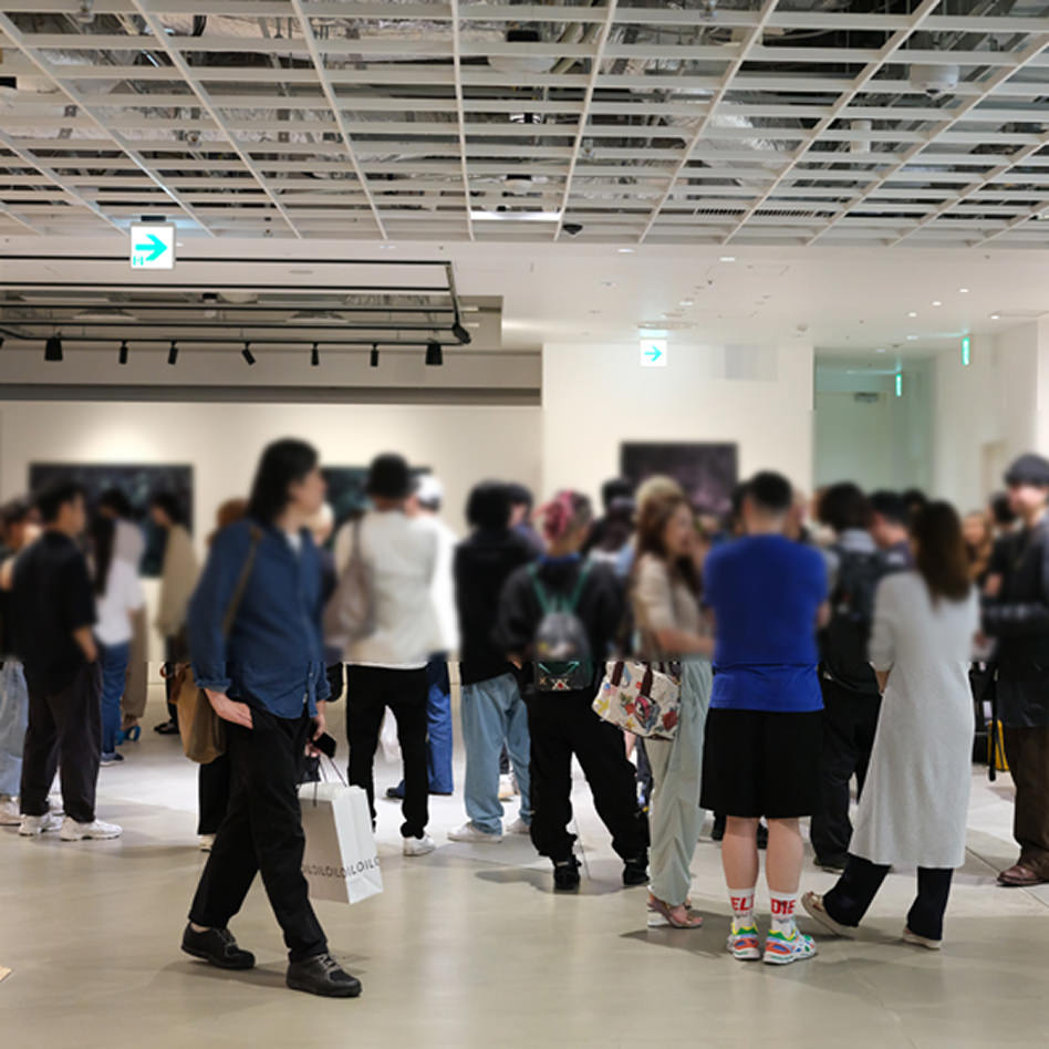 格子状の天井とスポットライトが印象的な広々としたギャラリー内で、多くの来場者が展示された写真パネルを鑑賞している風景。来場者の姿はプライバシー保護のためぼかされている。