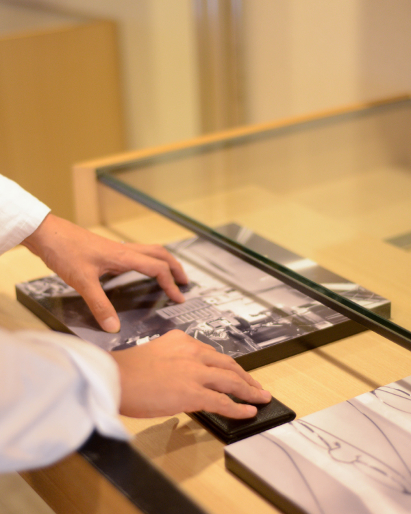 ガラス天板のある木のカウンターに、モノクロ写真のWALL DECORを並べる手元の様子。