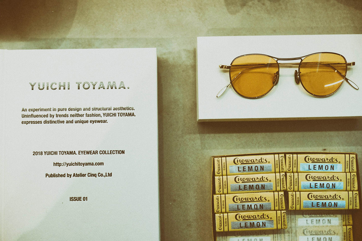 ブランド冊子と黄色い眼鏡、ミント菓子が並ぶディスプレイ