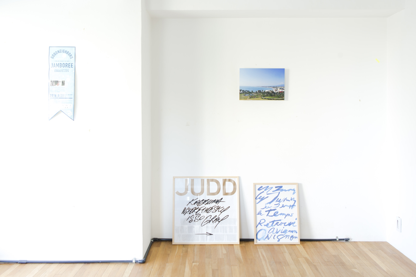 白い壁に小さなWALL DECOR、床にアートを置いた明るい部屋