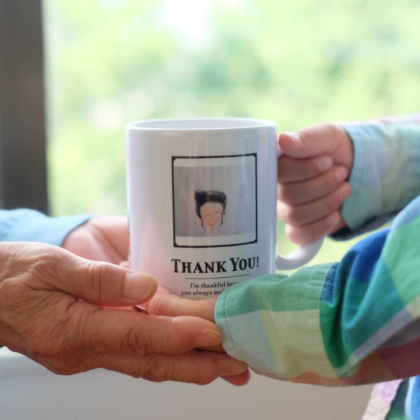 THANK YOU!」とプリントされたマグカップを子どもが手渡している様子。