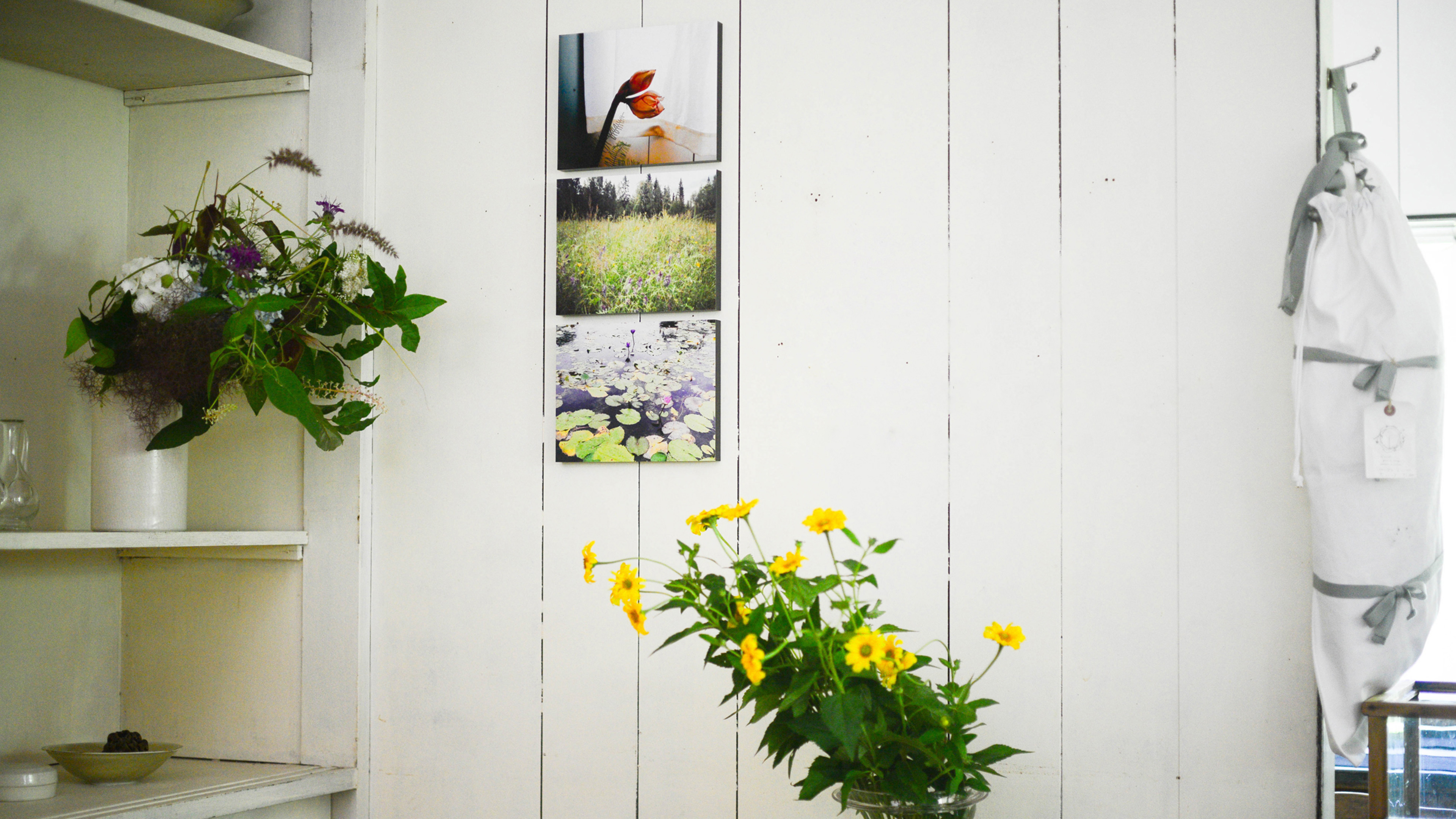 白い板壁にWALL DECOR カジュアルが飾られた、黄色い花が映える明るい部屋