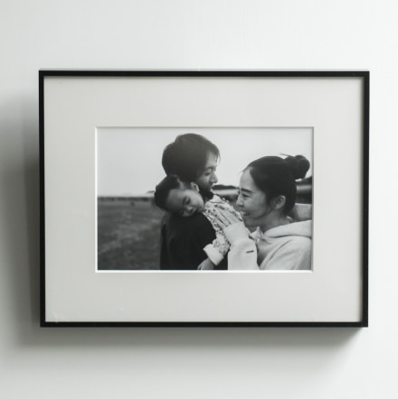 笑顔の家族のモノクロ写真が飾られた、黒縁フレームのWALL DECOR。