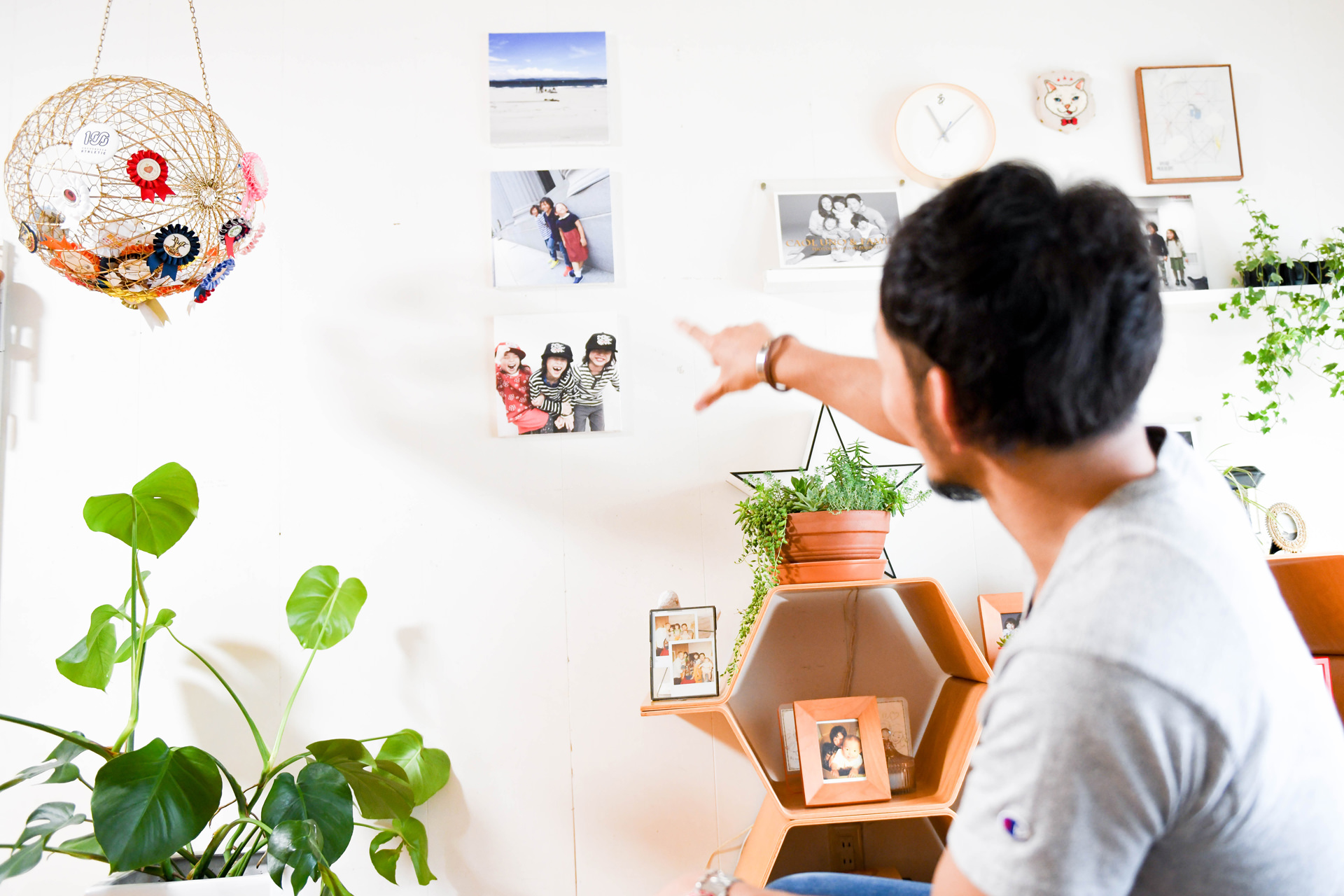 壁に飾ったWALL DECORを指差す男性。