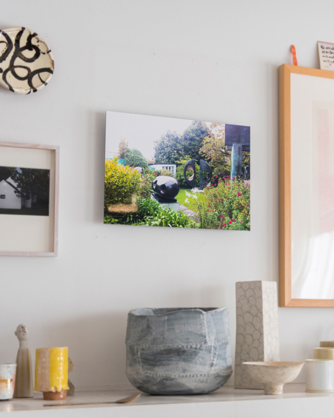 白い壁に庭の風景写真のWALL DECOR ミュージアムを飾り、下の棚に様々な器やオブジェを並べる。