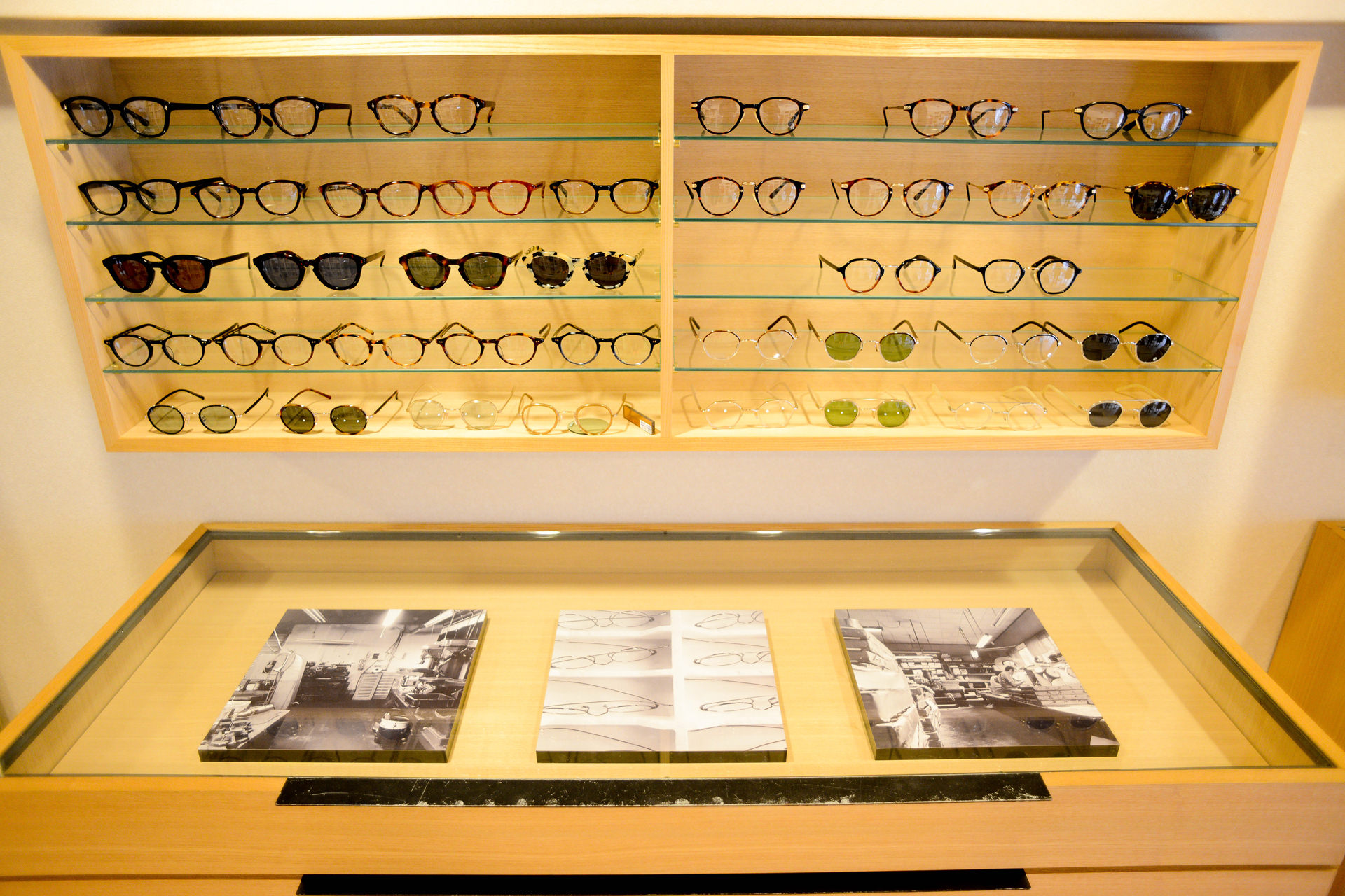 整然と眼鏡が並ぶディスプレイ棚と、その手前に置かれた3枚のWALL DECOR カジュアル。明るい店内の展示風景。