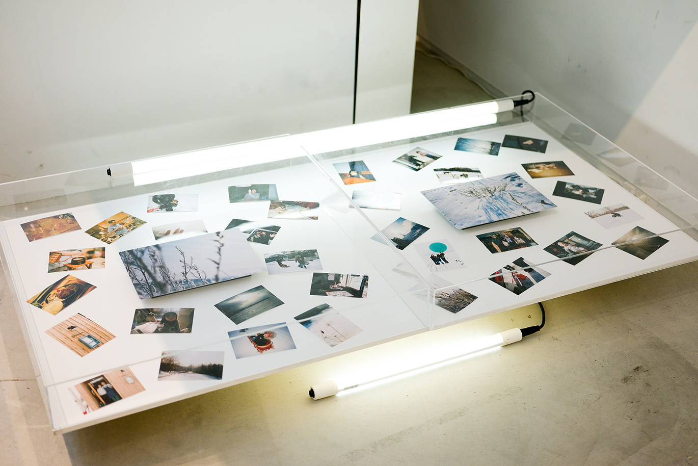 ライトパネルの上に置かれた、雪景色のWALL DECORと周囲に散りばめられた多くのスマホ・デジカメプリント