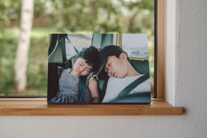 窓際に飾られた、車内で眠る子供たちの写真のWALL DECOR カジュアル。