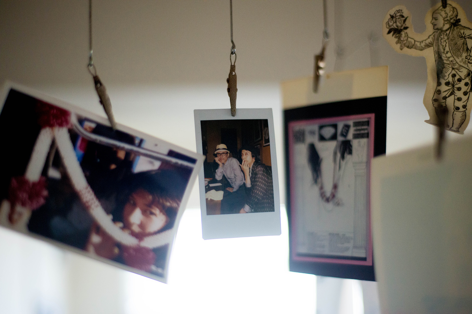 ワイヤーにクリップで留められたポラロイド写真やカード。空中に吊るして飾るフォトディスプレイの風景。