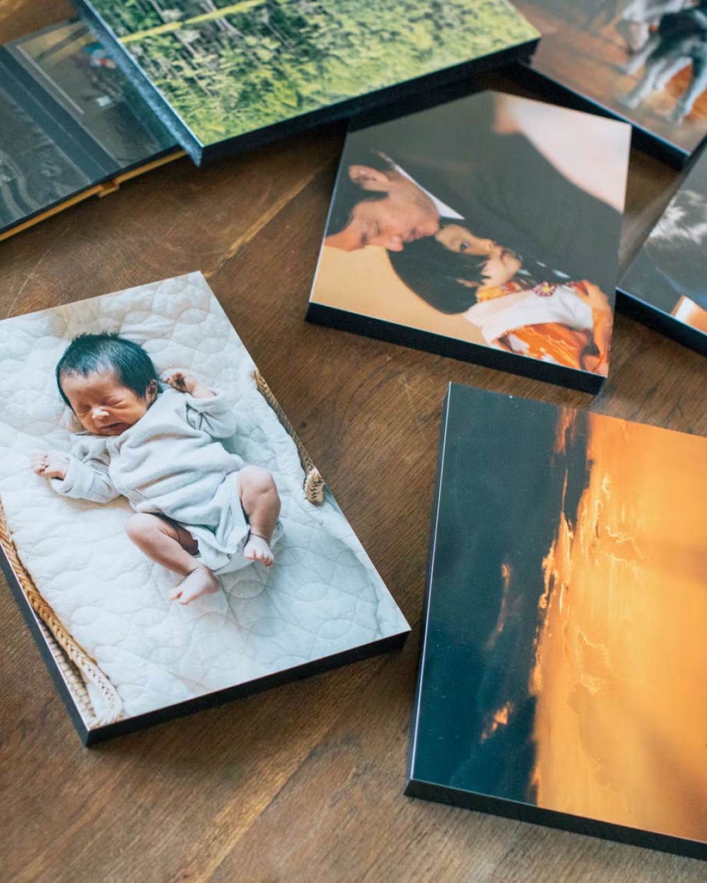 木のテーブルに置かれた、赤ちゃんや家族、夕焼けの風景など様々な写真のWALL DECOR。
