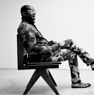 迷彩柄の服を着た男性が椅子に座る、モノクロ写真