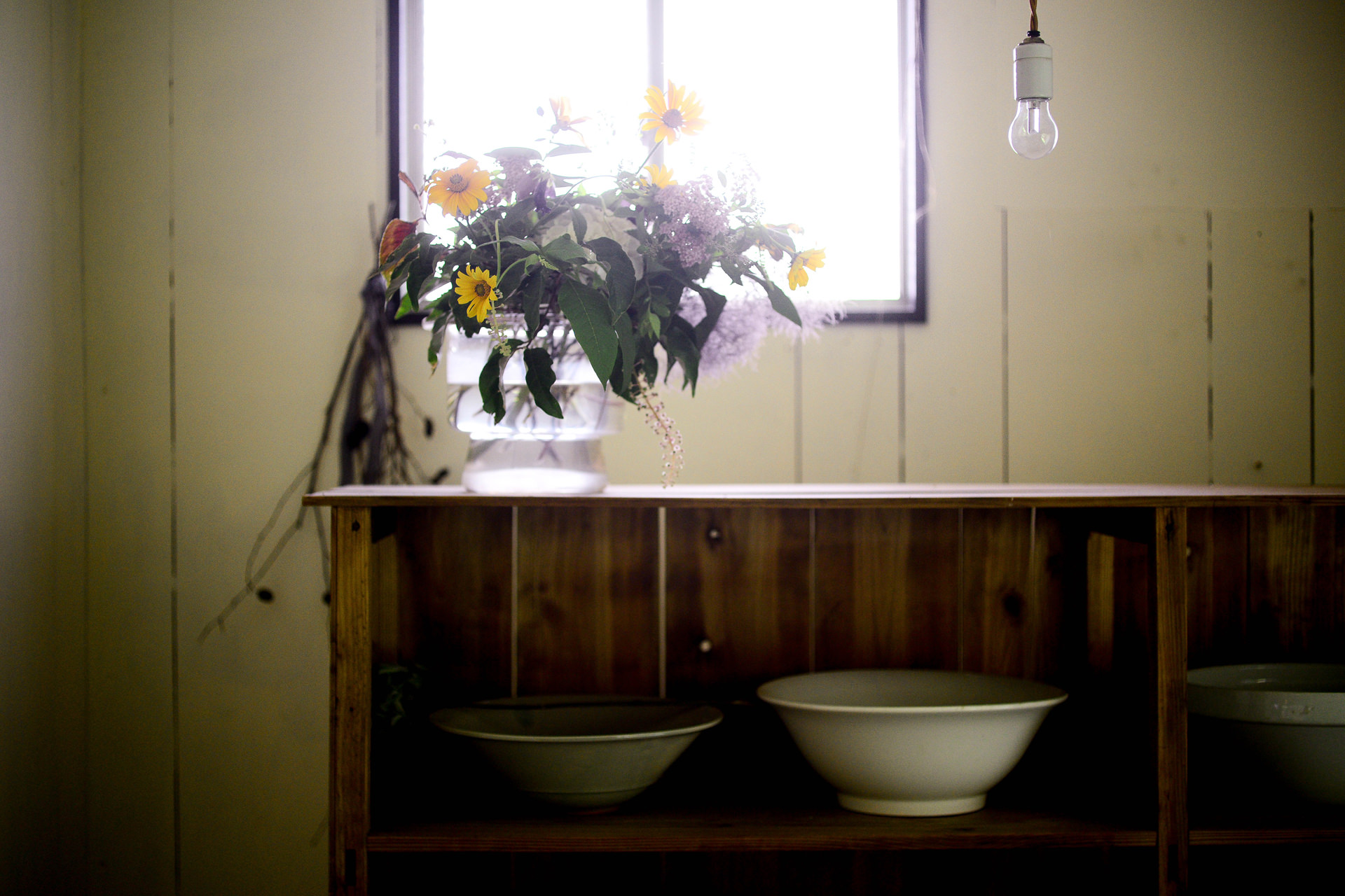 窓辺の棚に置かれた花瓶と、柔らかい光が差し込む落ち着いた室内。