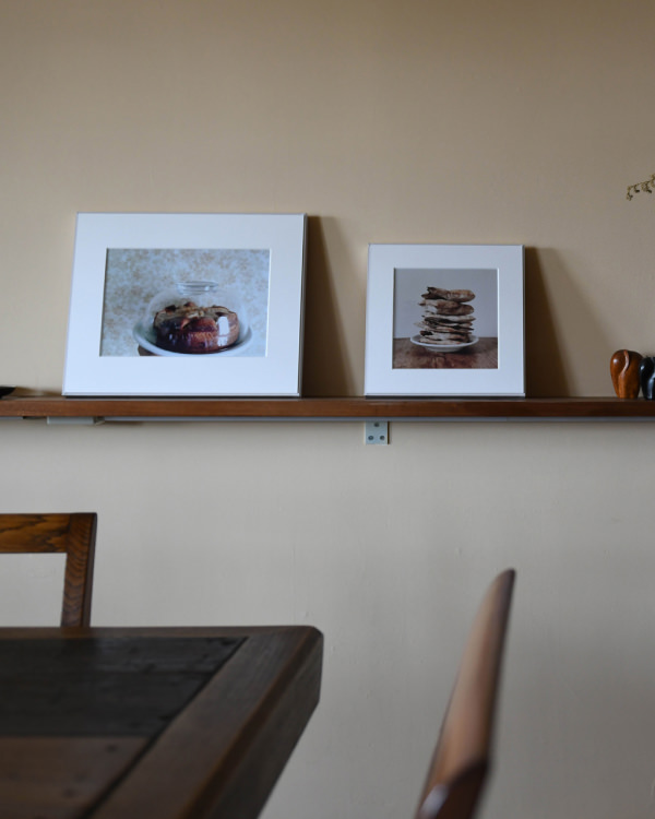 ダイニングテーブル越しの壁の棚に、お菓子とパンケーキの写真のWALL DECORを2枚並べて飾る。