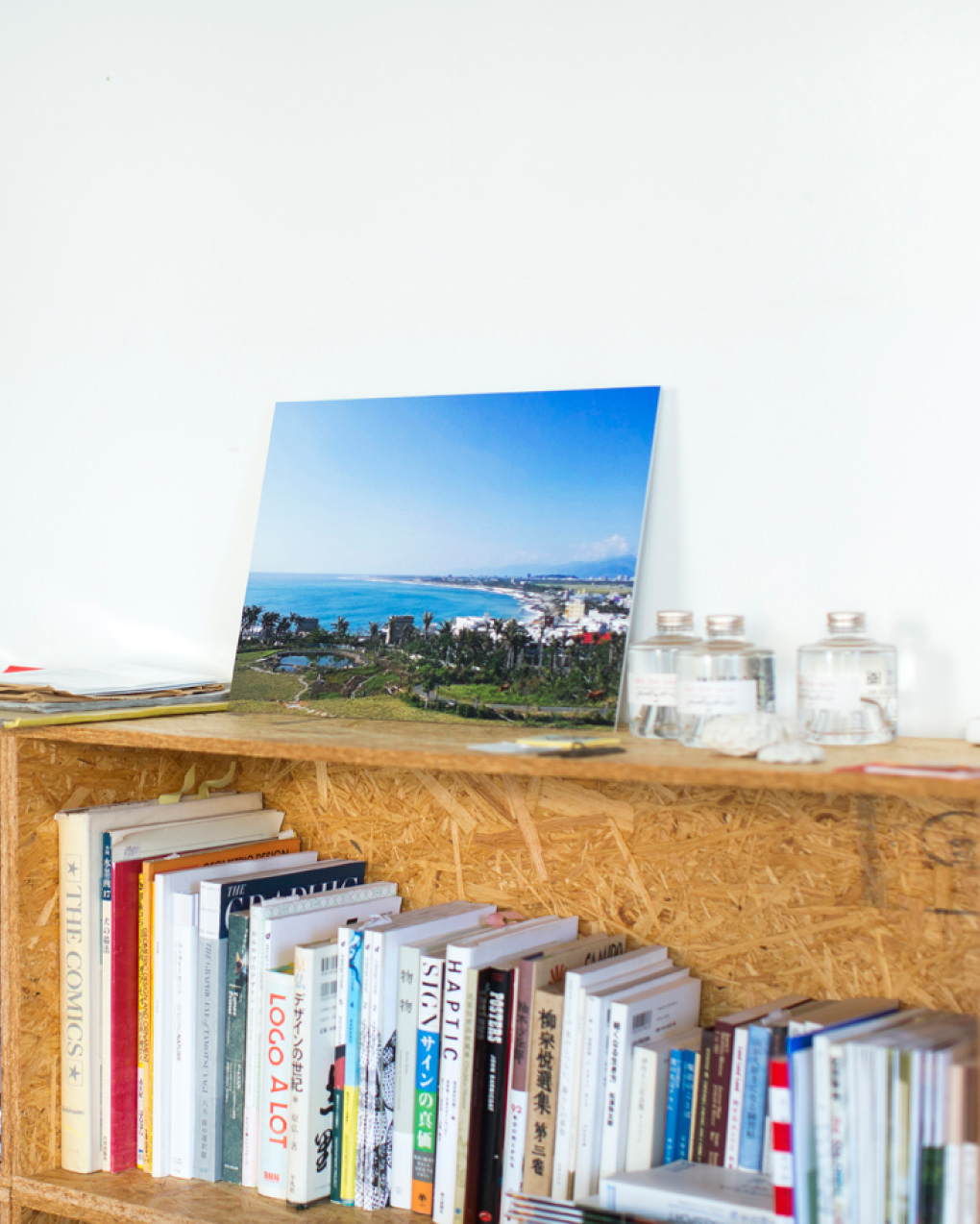 本が並ぶ棚の上に、青い海と街並みの風景のWALL DECORを飾る。
