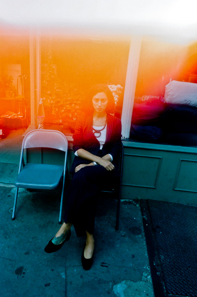 店先で椅子に座っている女性を、暖かい光が包み込む幻想的な写真