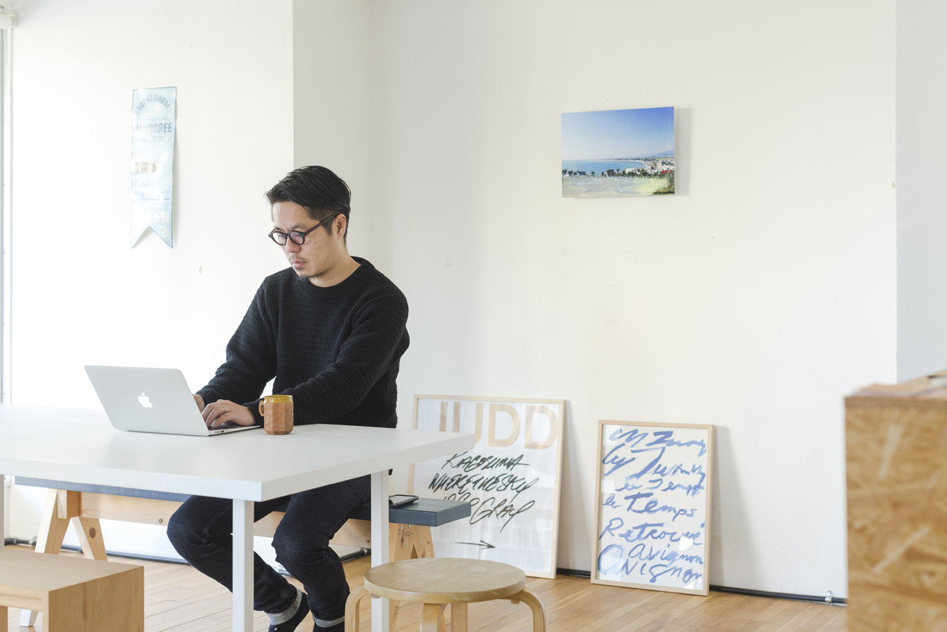 ノートパソコンで作業する男性と壁に飾られたアート