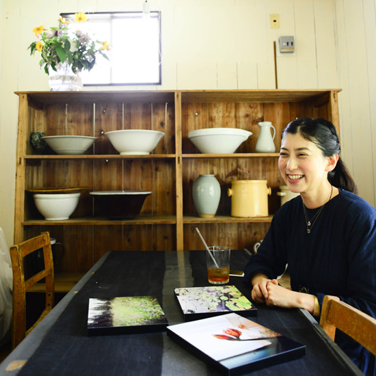 テーブルに置かれた3枚のWALL DECOR ギャラリーを見て微笑む平井 かずみさん