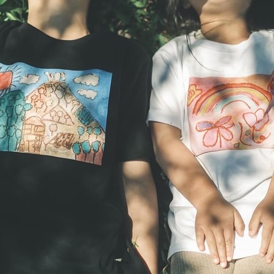 子供の絵をプリントしたフォトグッズTシャツを着て、並んで寝転ぶ二人。