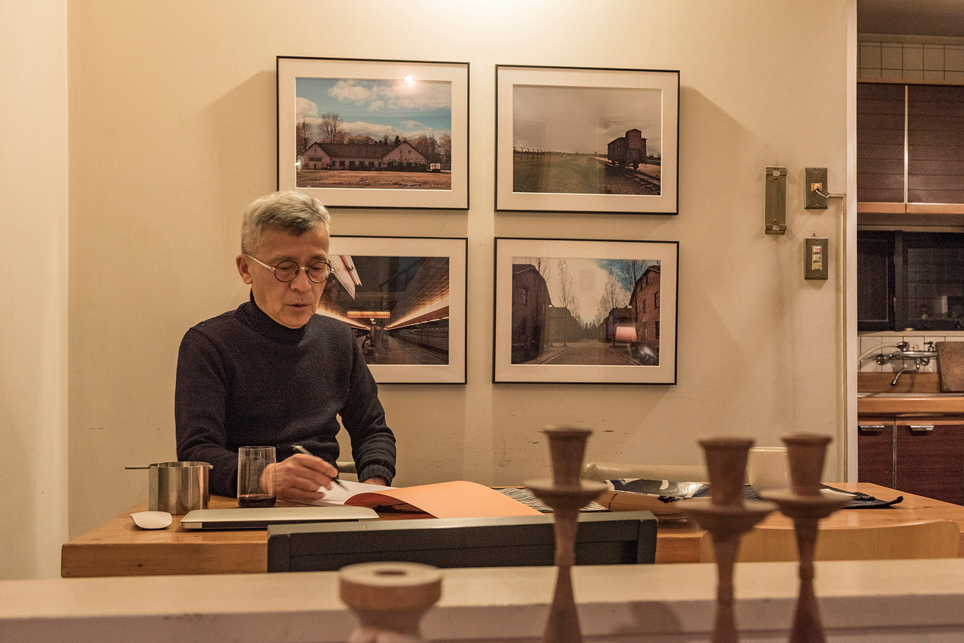 書斎の壁に並ぶWALL DECOR ギャラリーを背に書き物する男性