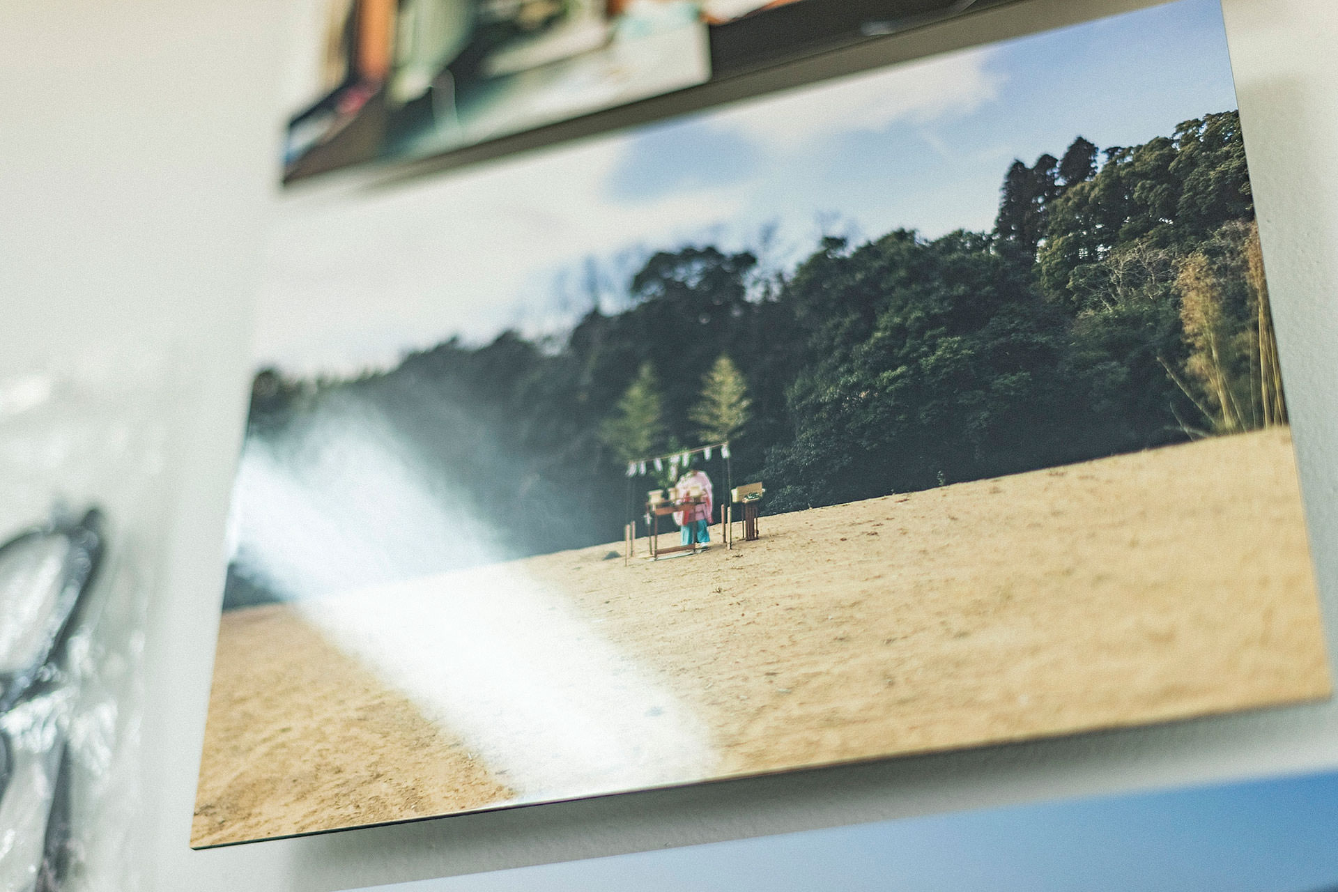 砂地の中央に小さな設えがあり、背後に深い森が広がる風景を捉えたWALL DECOR ミュージアムの接写。