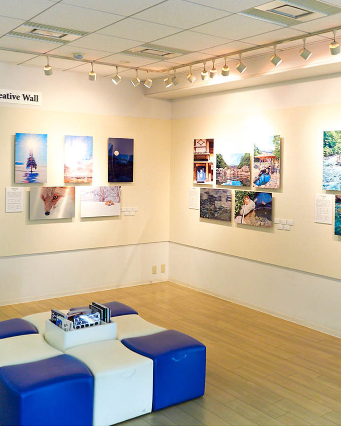 スポットライトに照らされたギャラリーの壁面に、キツネや冬の景色、川辺の風景など、大小さまざまな写真パネルが整然と展示されている。