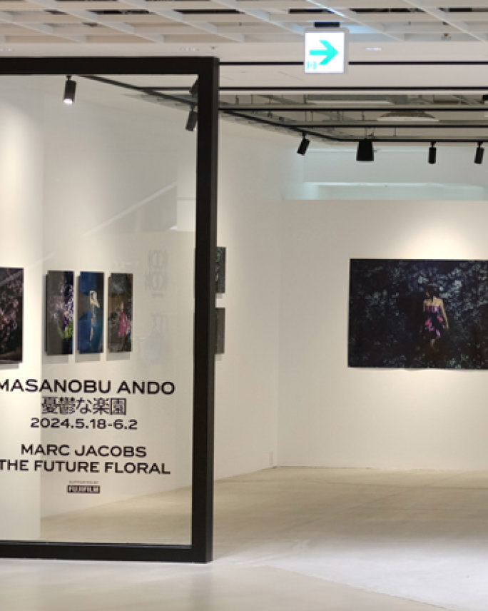 ガラスに「MASANOBU ANDO 憂鬱な楽園」などの文字が書かれた、写真作品が並ぶ展示会場の風景。