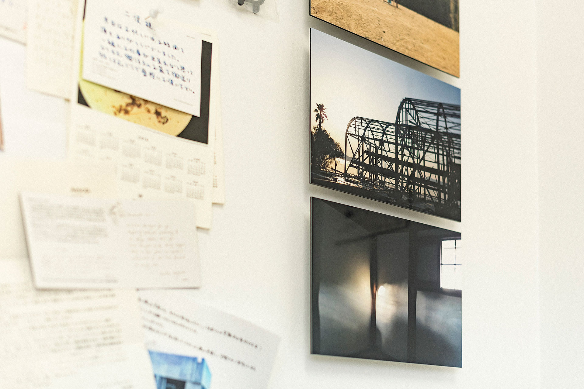 構造的な建築物と光の射し込む室内を捉えた2枚のWALL DECOR ミュージアムの接写。左側には手書きのメモやカードが壁にピンで留められている。