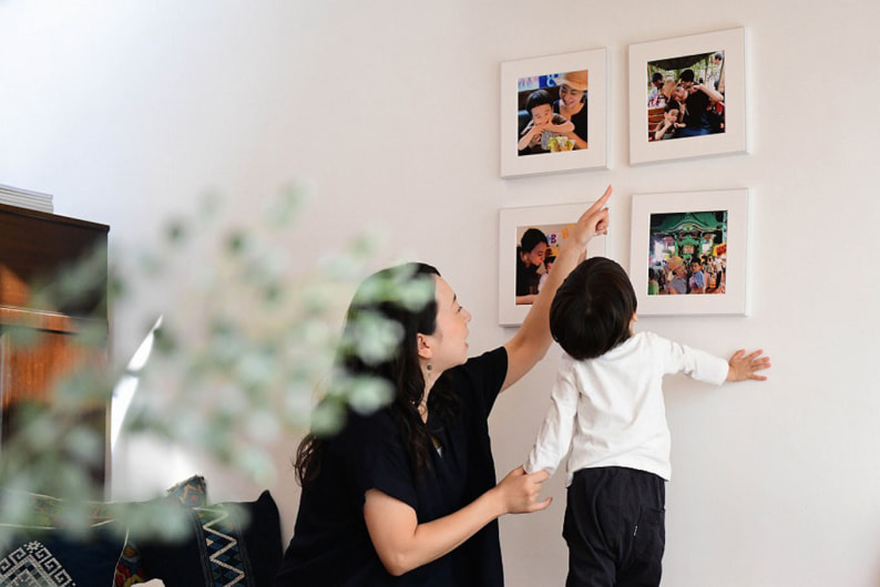 白い壁に4枚飾られた、家族写真のWALL DECOR ギャラリー。親子が楽しそうに写真を指差しながら眺めている。