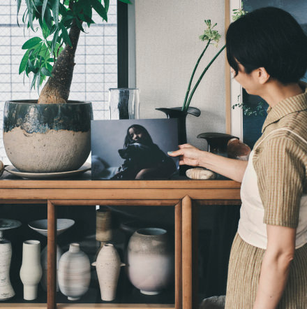 女性が木製の飾り棚に、子どもと犬の写真のWALL DECORを飾っている様子。