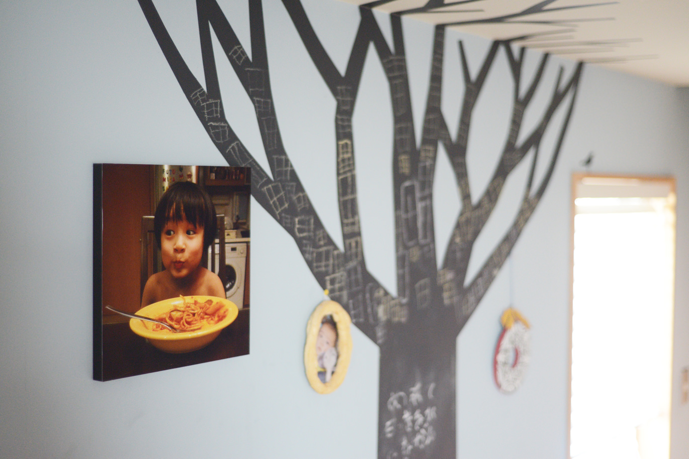 壁に飾られた子供が写っているWALL DECOR カジュアルと木のデザイン